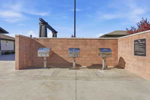 Outdoor grilling station featuring three stainless steel grills, a privacy wall constructed from orange-hued brick, and a concrete patio surface