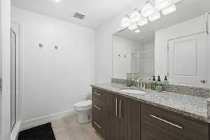Bathroom featuring a dark wood-finish vanity with an integrated sink, a speckled countertop, and a large wall-mounted mirror