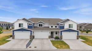 Townhome exterior featuring white and blue siding, a multi-gabled roof, and stone accents