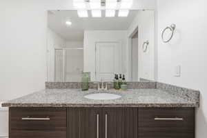 Bathroom vanity featuring a speckled countertop, integrated sink, and wood-finish cabinetry with brushed nickel hardware
