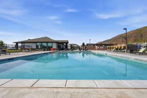 Large outdoor swimming pool with concrete decking, surrounding a modern clubhouse building
