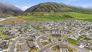 Expansive residential development featuring modern homes and townhomes, surrounded by lush green mountains and open fields