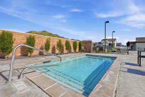 Outdoor pool with integrated steps and a stainless steel handrail, surrounded by concrete decking