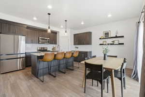 Open-concept kitchen and dining area featuring wood-finish LVP flooring, recessed lighting, and white walls