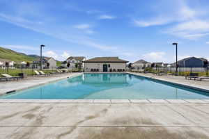 Community swimming pool with surrounding concrete decking, perimeter fencing, and a nearby clubhouse building