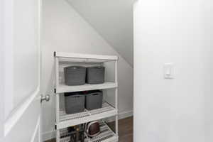 Closet storage featuring white shelving units, an angled ceiling line, and light wood-finish flooring