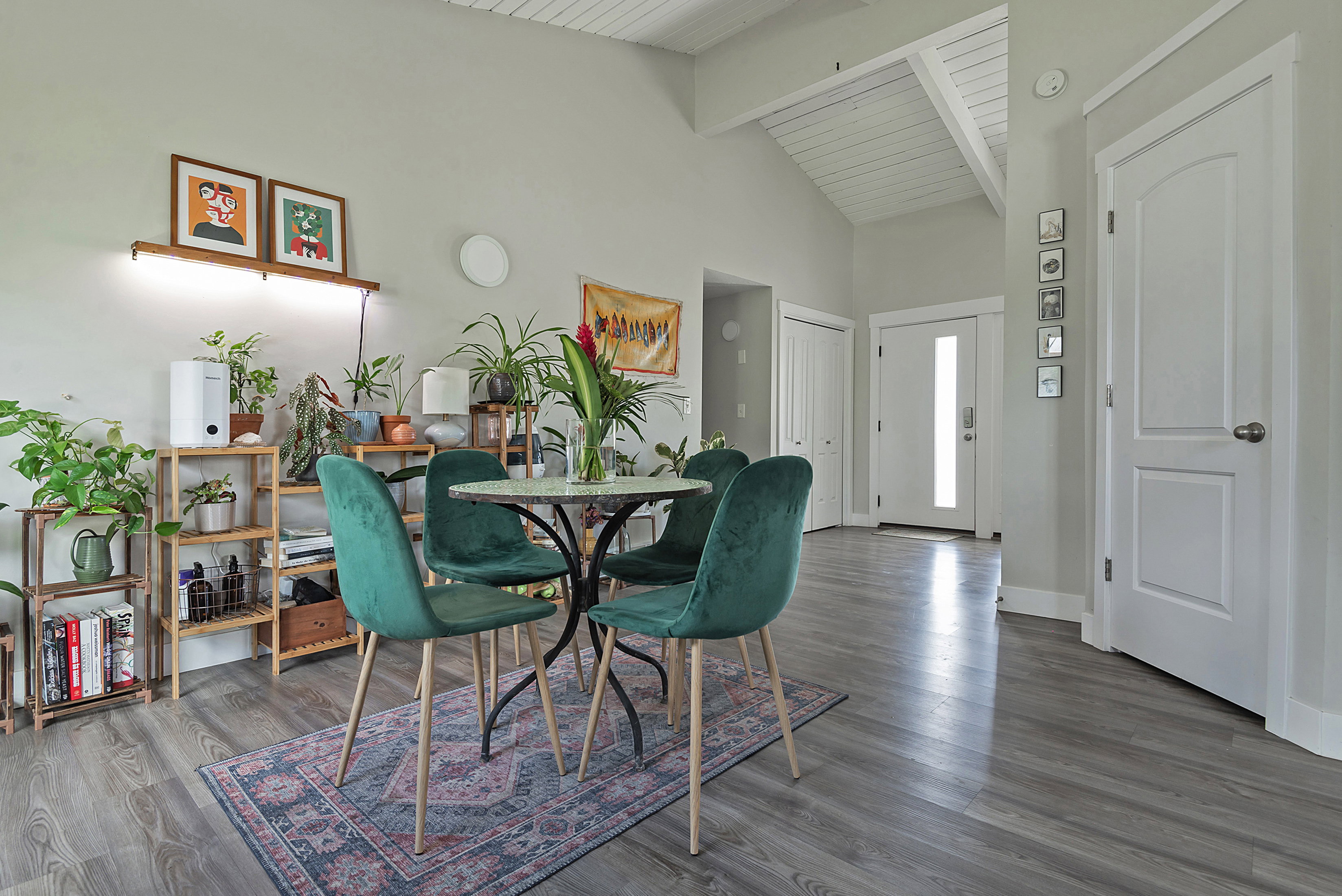 Spacious interior featuring wood-finish flooring, vaulted ceilings with exposed beams, and a modern entry door with a vertical light panel