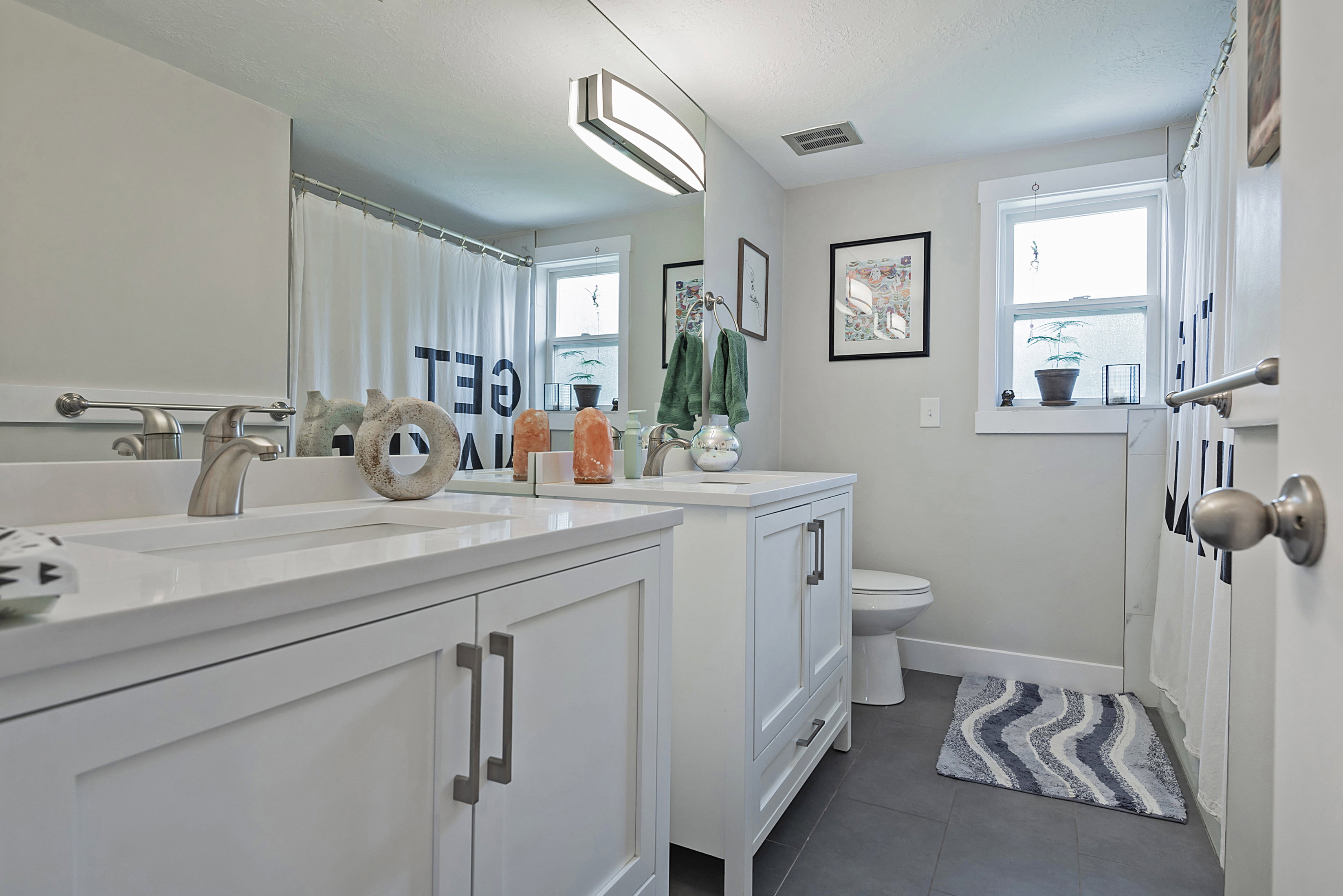 Modern bathroom featuring a dual vanity with white shaker-style cabinetry, integrated sinks, and brushed nickel hardware