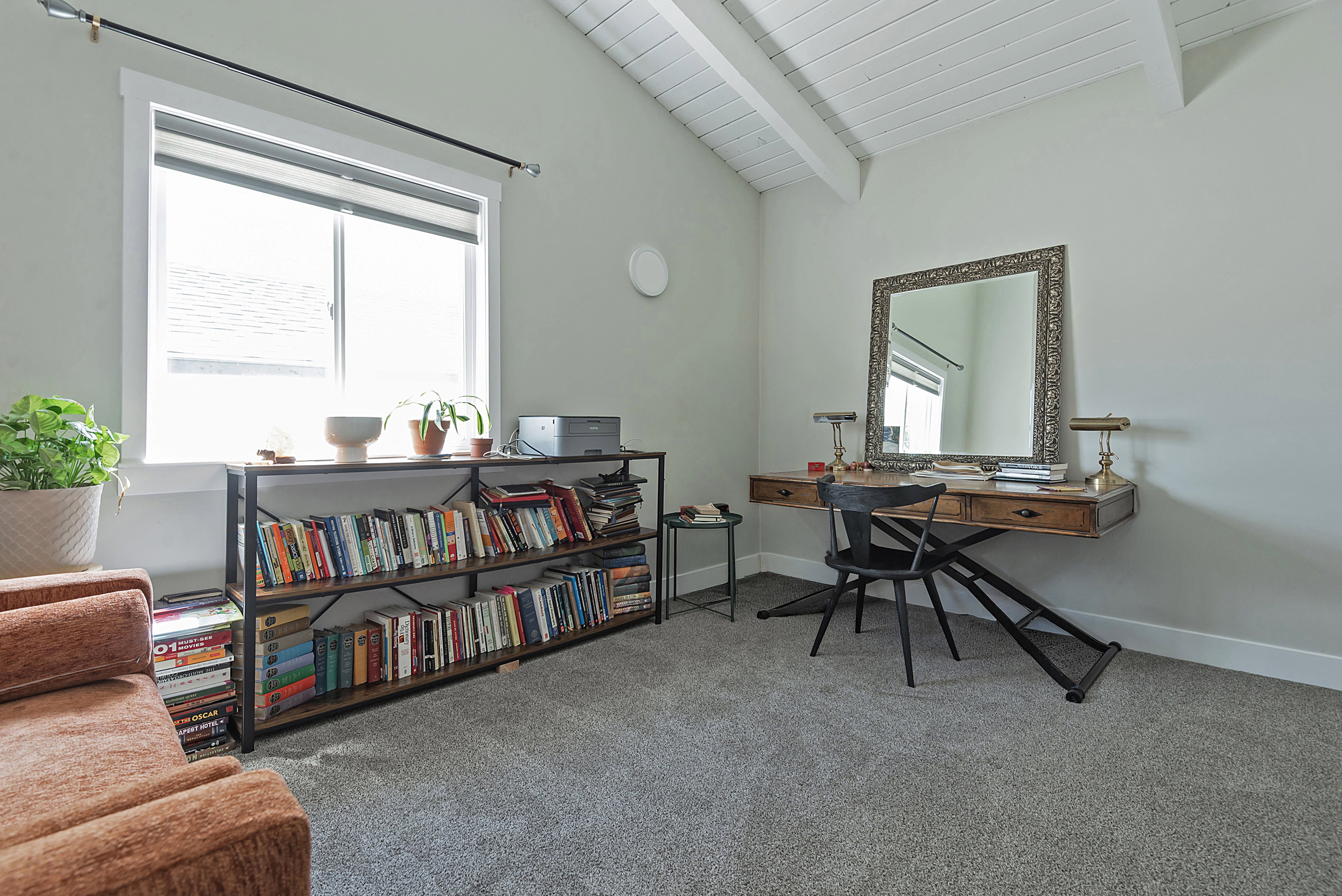 Vaulted ceiling featuring exposed white beams, light gray carpet flooring, and a large window with white trim