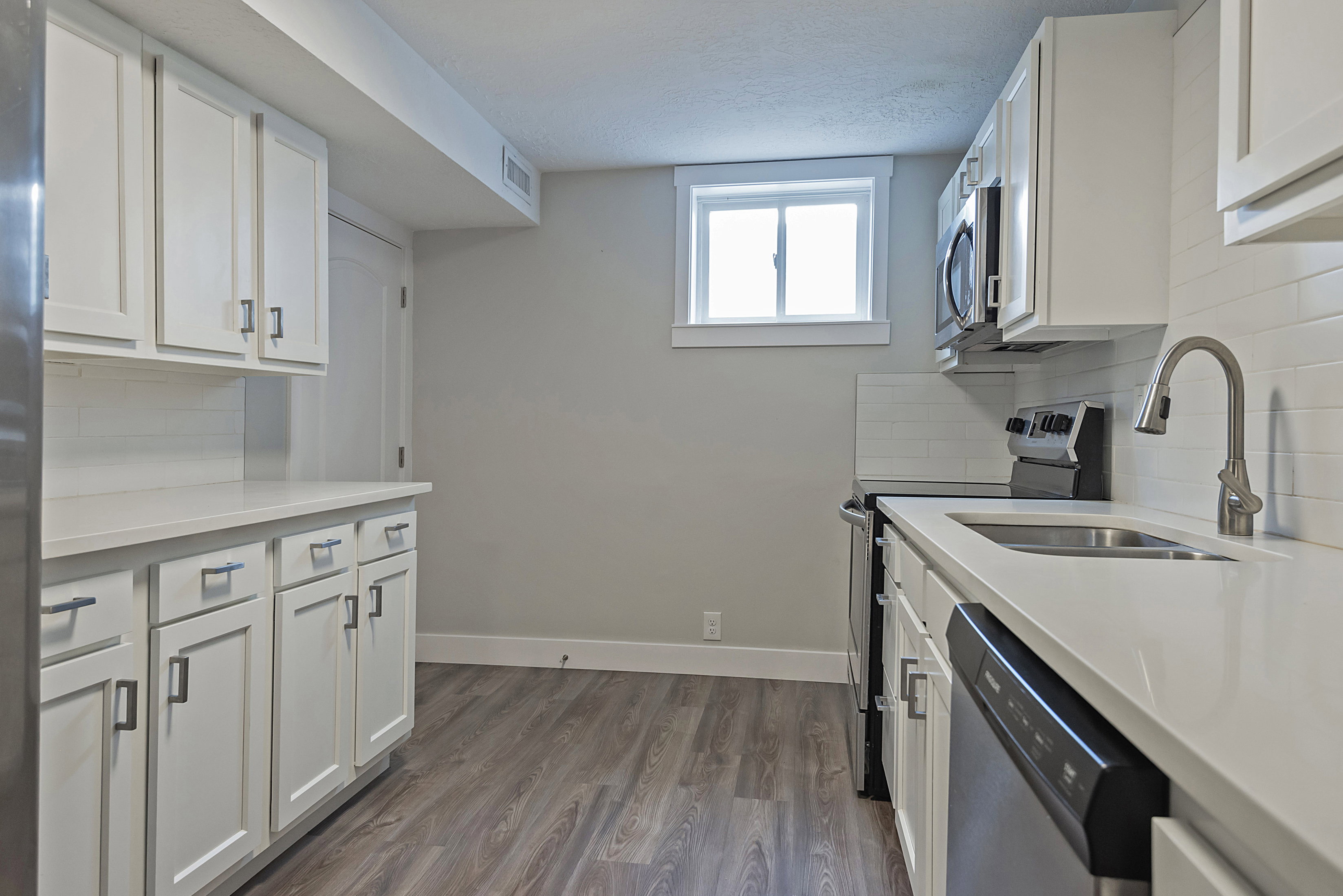 White shaker cabinetry with modern hardware, light-toned countertops, and a subway tile backsplash