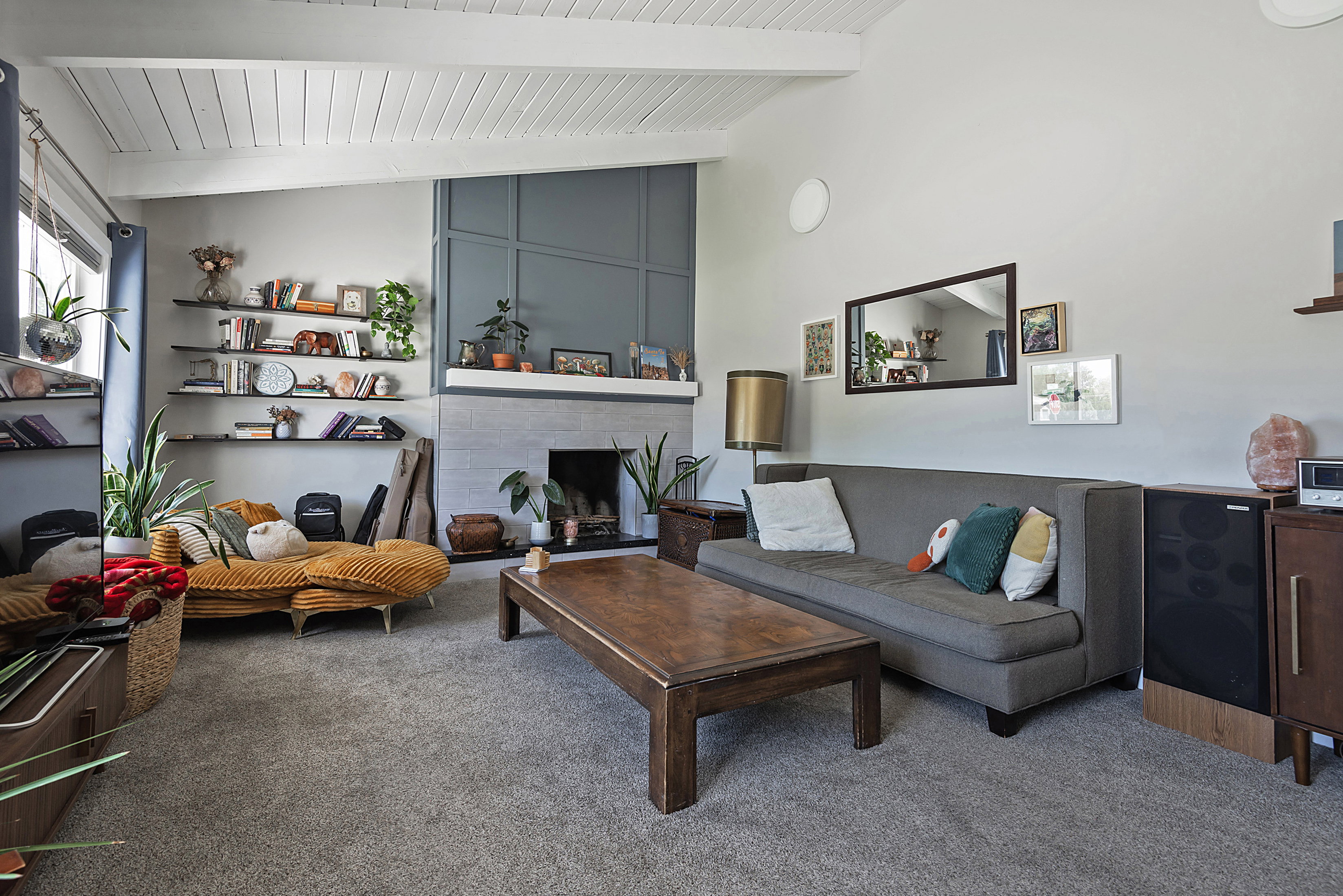 Vaulted wood-paneled ceilings highlight this living space, featuring a fireplace with a stone surround and a decorative paneled accent wall