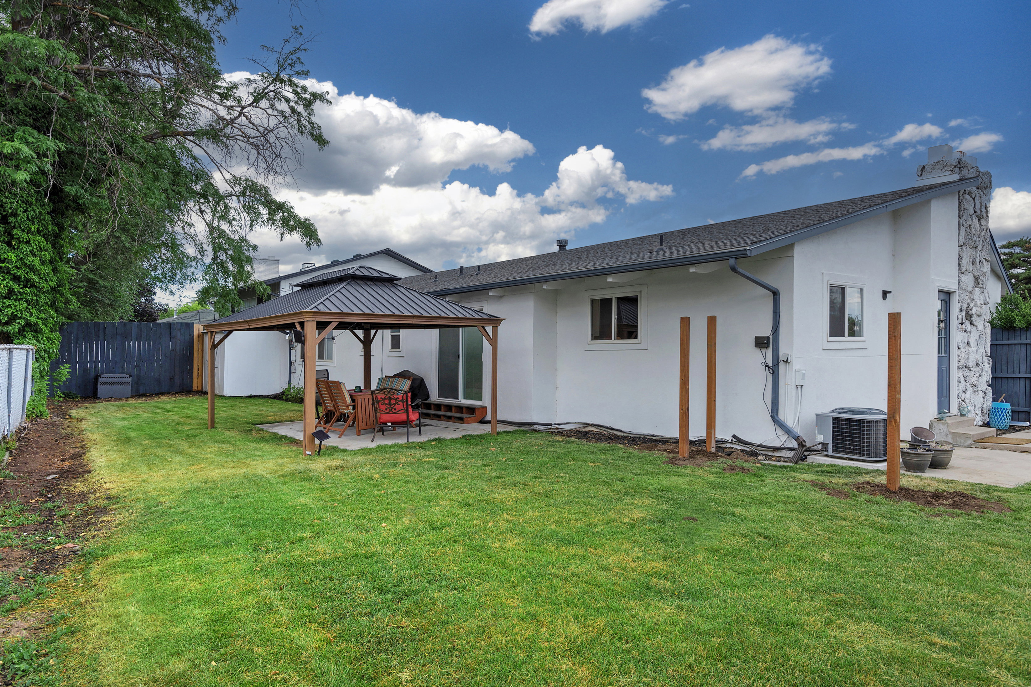 Expansive grassy yard with a concrete patio featuring a permanent gazebo structure