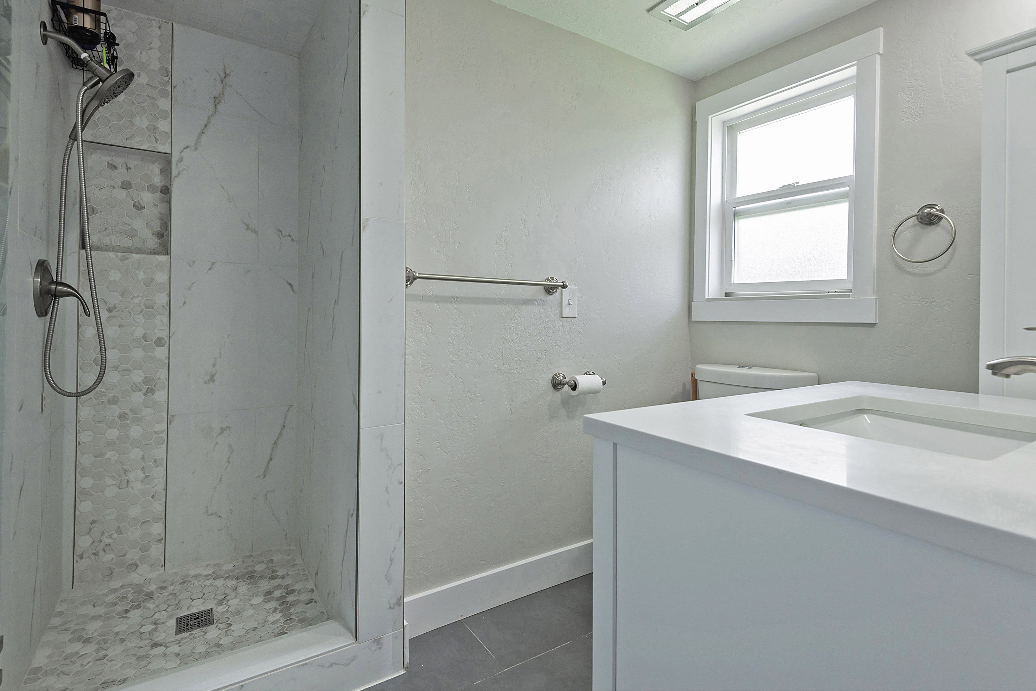 Shower with glass enclosure, large format tile walls, and a mosaic tile floor