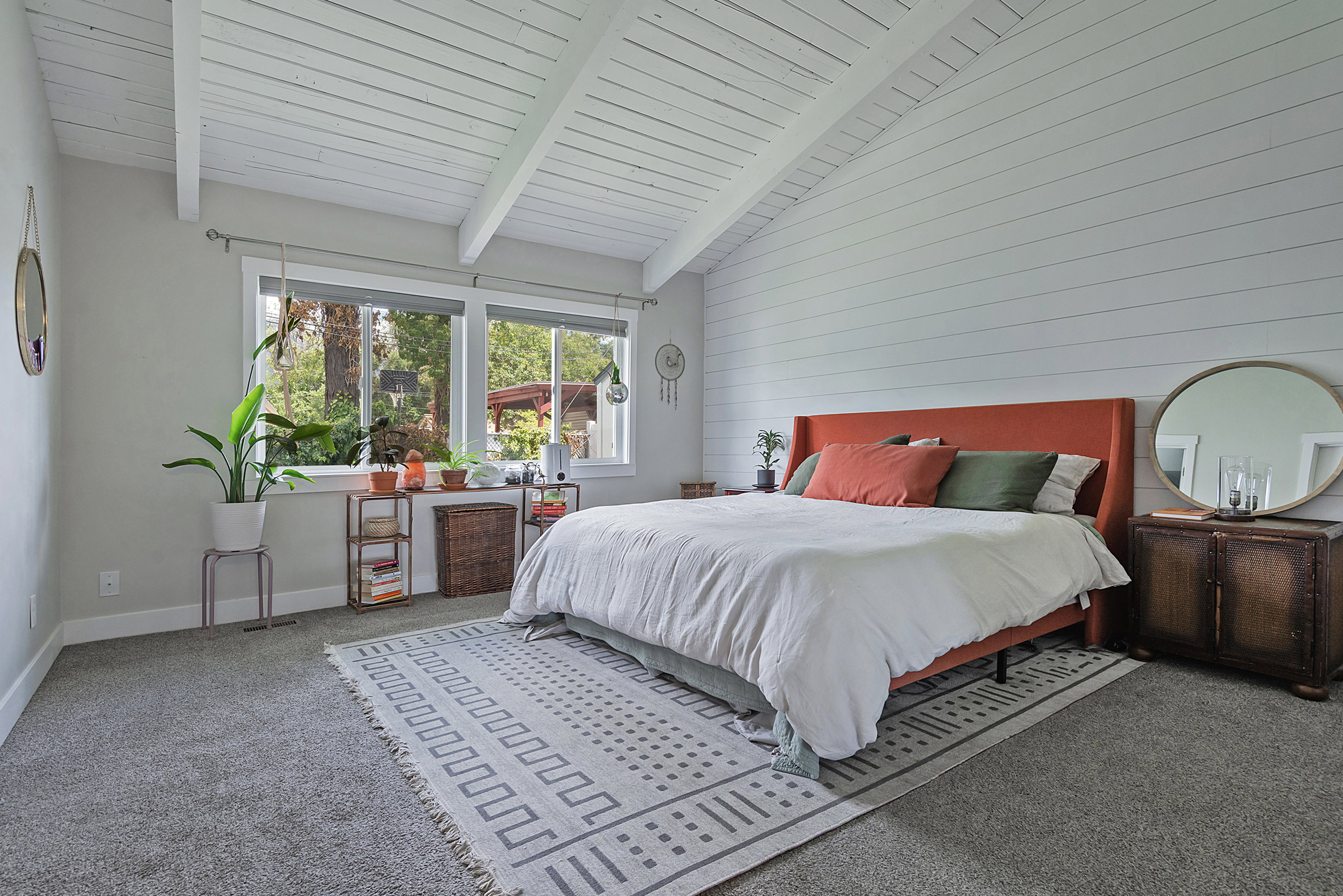 Vaulted ceiling with white wood paneling, shiplap accent wall, and dual windows