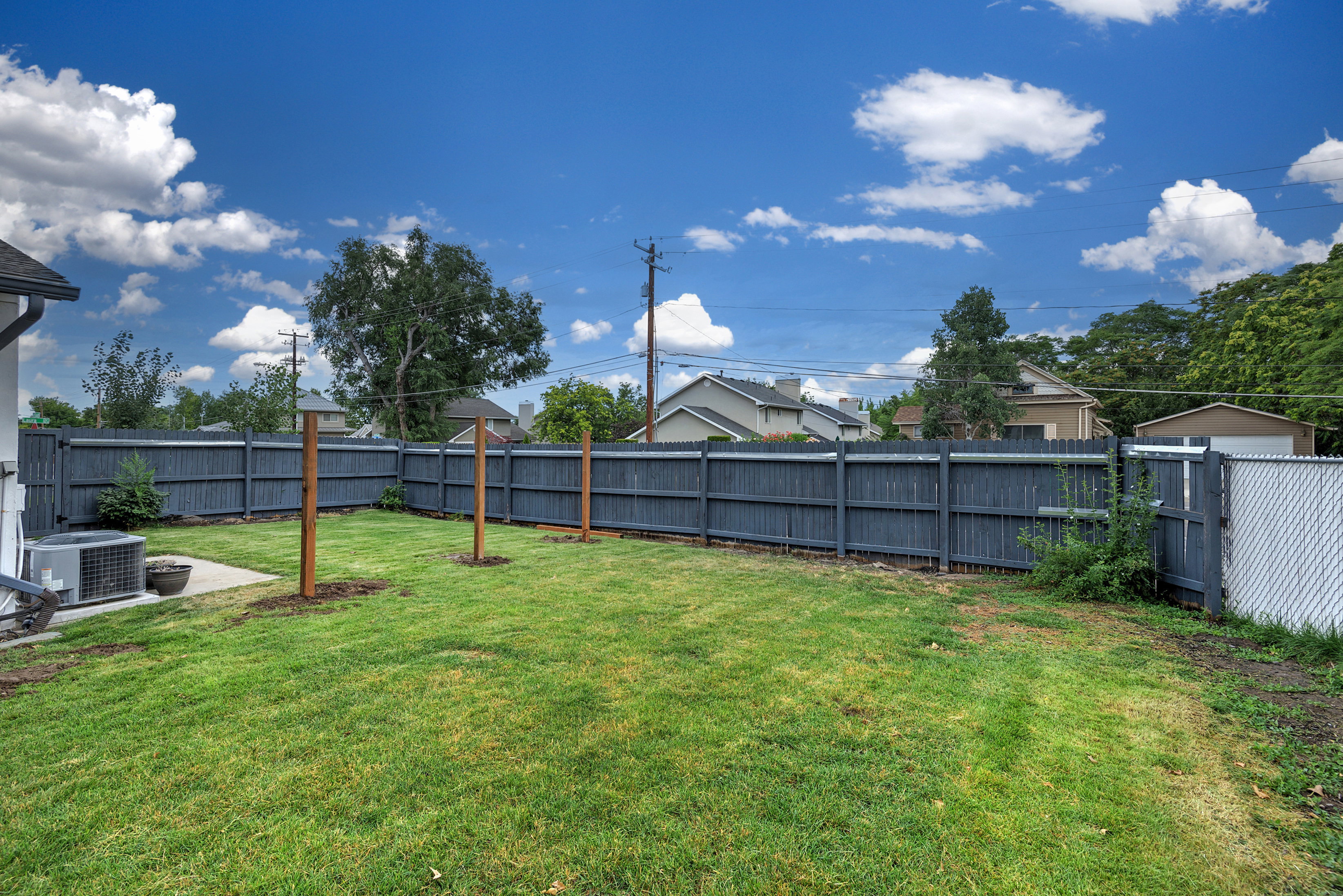Expansive, manicured lawn with a privacy fence and chain-link gate