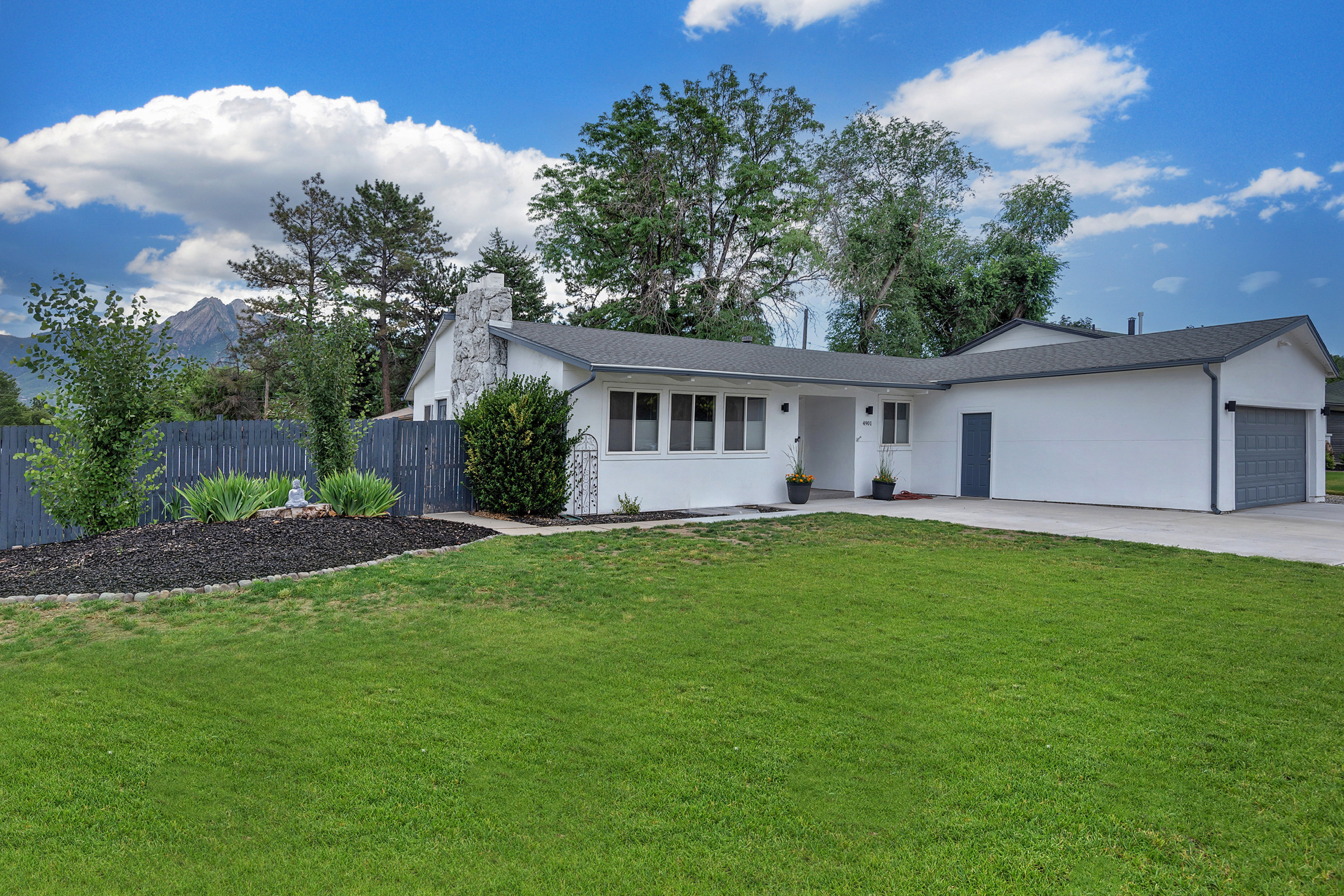 White stucco exterior with dark gray trim and a prominent attached garage