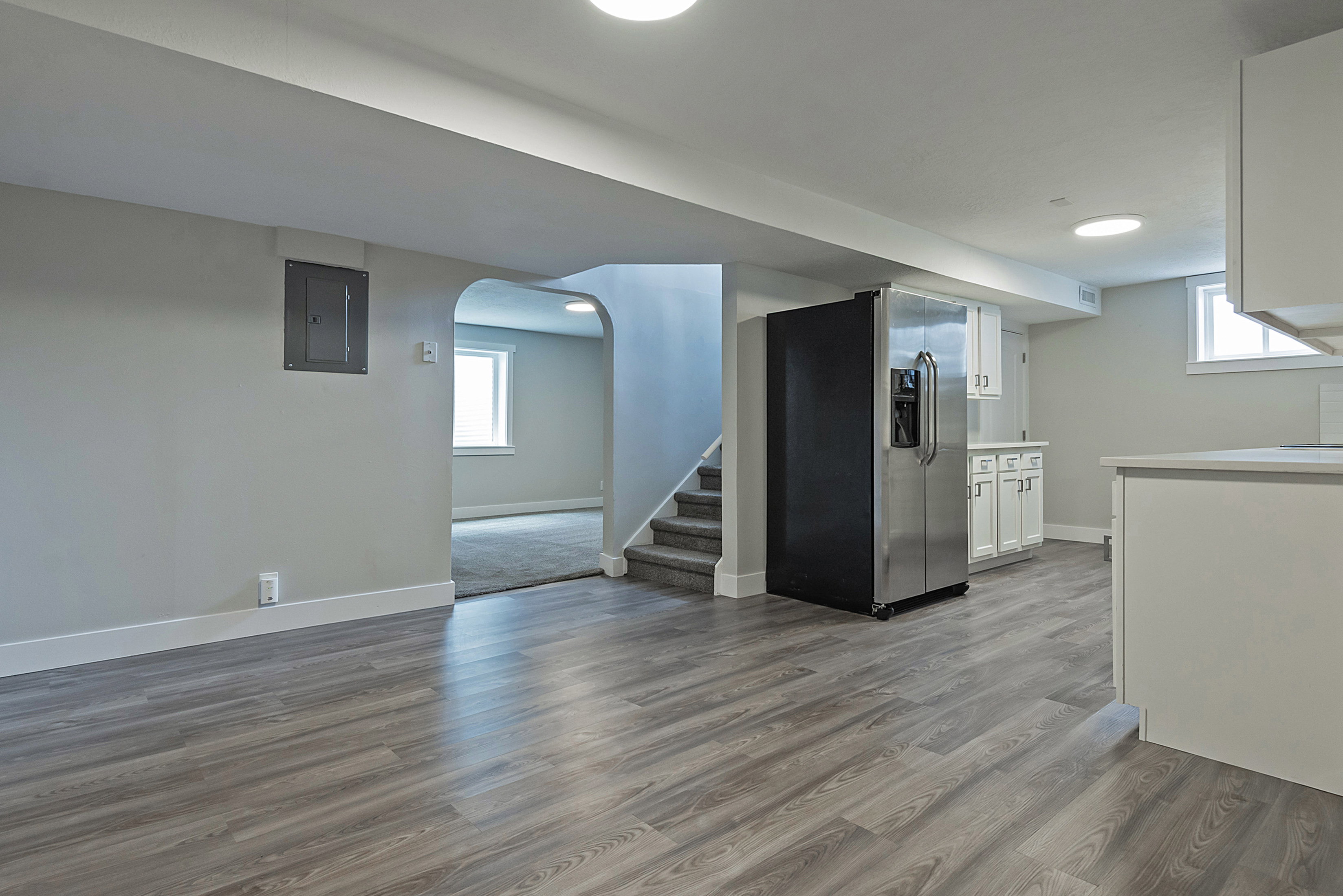 Open-concept interior featuring wood-finish flooring, recessed lighting, and a stainless steel refrigerator