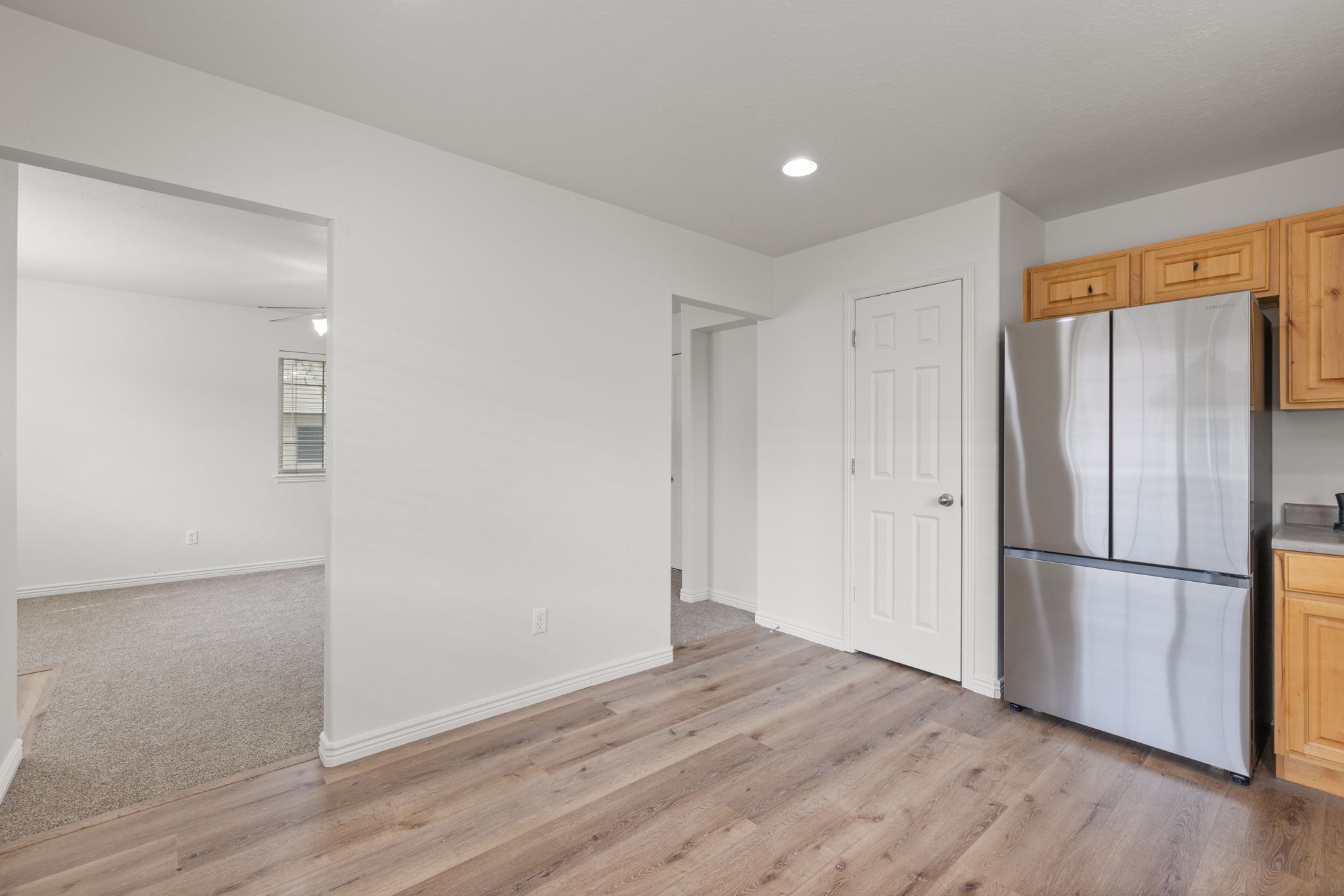 Open eat-in kitchen with natural wood cabinetry, LVP flooring, recessed lighting, and new stainless steel appliances