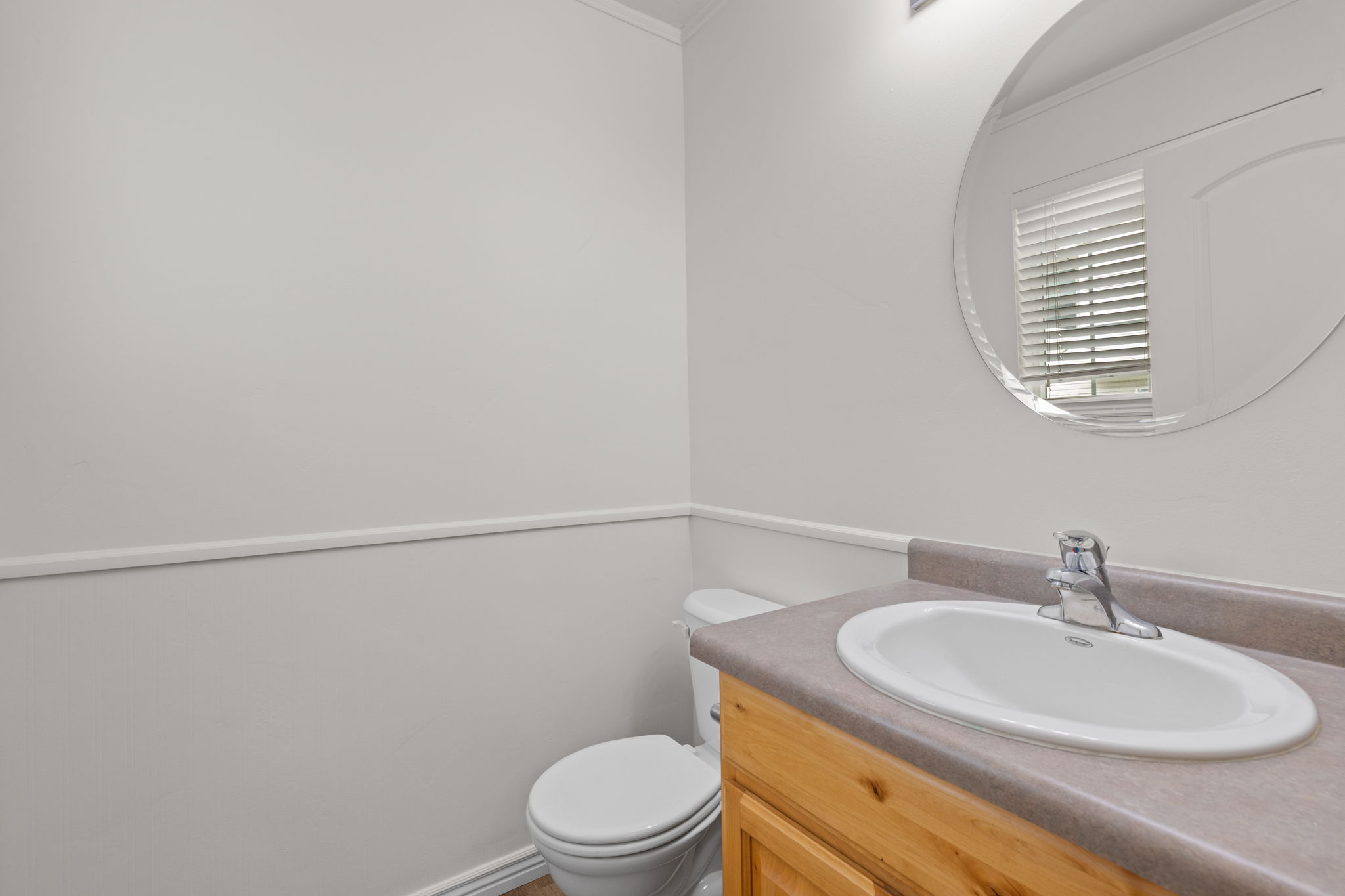Main floor powder room with light neutral paint and sink with natural wood cabinetry