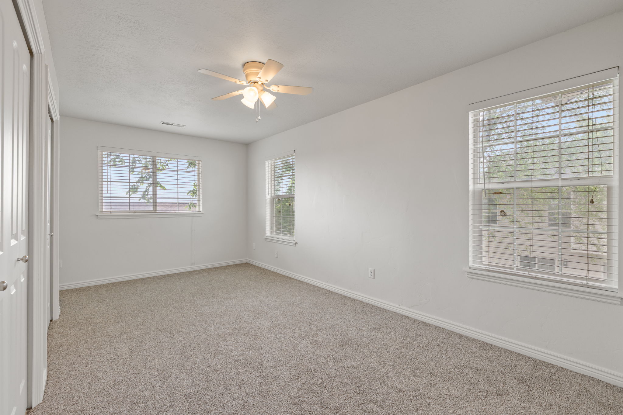Primary bedroom with brand new carpet and light neutral paint, abundant natural light, and ceiling fan