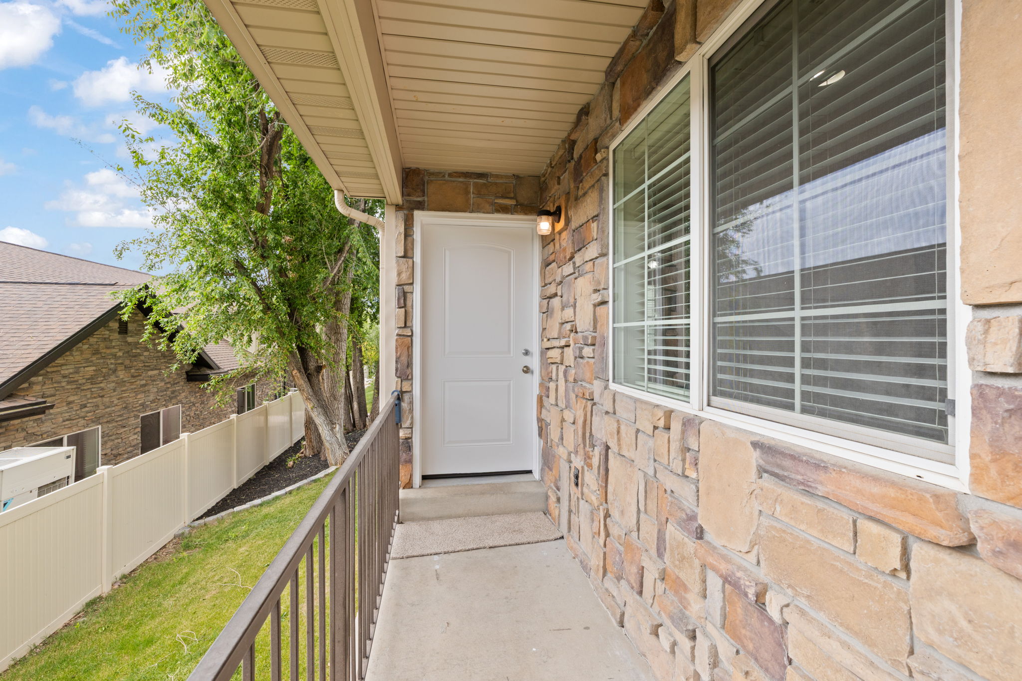 Covered front porch with neutral colored stacked stone facade