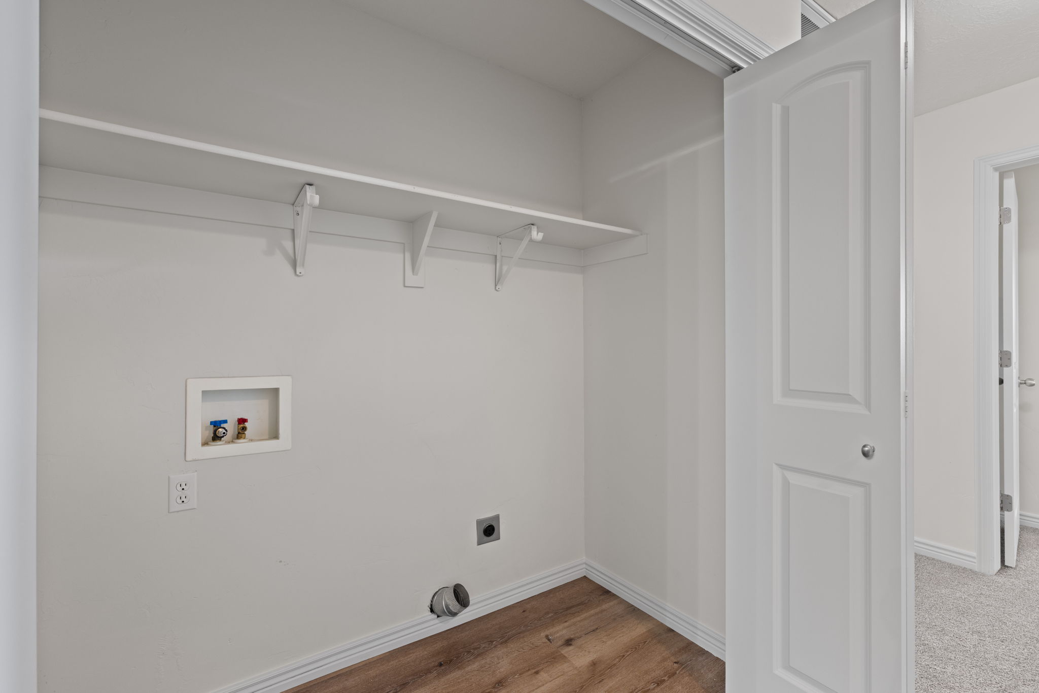 Second floor laundry area with shelving and LVP flooring