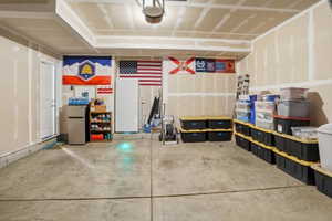 Spacious garage featuring a concrete floor, high ceilings with exposed joists, and a side-entry door