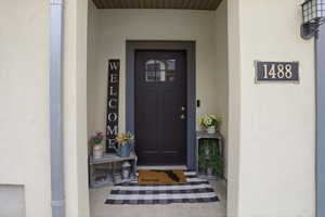 Recessed entry featuring a dark-paneled door with upper window panes, textured exterior finish, and contrasting dark trim