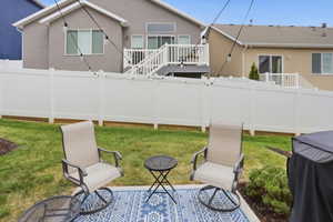 Expansive backyard featuring a manicured lawn, white privacy fencing, and string lighting
