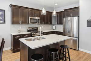 Modern kitchen featuring dark wood cabinetry, white countertops, and stainless steel appliances