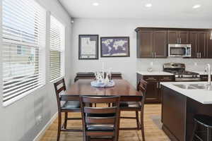 Contemporary kitchen and dining area featuring rich wood-finish flooring, white walls, and recessed lighting