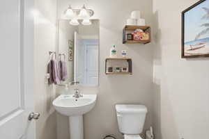 Pedestal sink with a polished chrome faucet, rectangular wall-mounted mirror, and a three-light vanity fixture