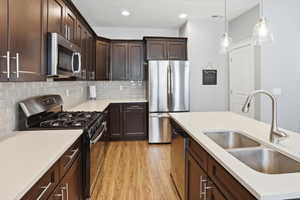 Contemporary kitchen featuring dark wood cabinetry, light-toned countertops, and a subway tile backsplash