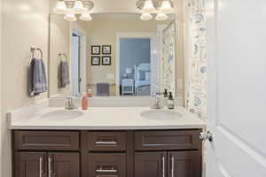 Dual sink vanity with dark wood-finish cabinetry, light-toned countertop, and undermount sinks
