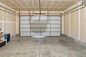 Spacious garage with a sectional overhead door, concrete flooring, and unfinished walls