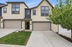 Multi-story stucco exterior with contrasting trim, a two-car garage, a covered entry, and a concrete driveway