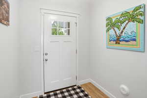 White paneled entry door with an upper window featuring decorative grilles, framed by white trim