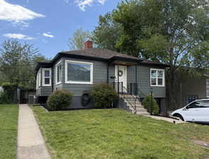 Bungalow/Cottage featuring dark siding, white trim, and a prominent front entrance with a covered porch