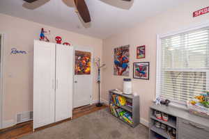 Bright room featuring a ceiling fan, window with blinds, hardwood flooring, and light-toned walls
