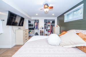 Primary Suite Bedroom featuring wood-finish flooring, a ceiling fan with integrated lighting, recessed lighting, and a window with horizontal blinds