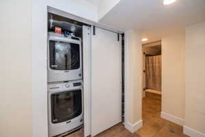 Integrated laundry closet featuring a stacked washer and dryer unit, barn-style sliding door, and recessed lighting