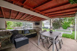 Covered concrete patio with exposed red-painted ceiling beams, and porch swing