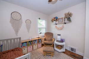 Room featuring a window with blinds, a ceiling fan, and hardwood flooring