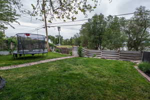 Expansive yard featuring a manicured lawn, a stone-lined pathway, and a rustic timber fence