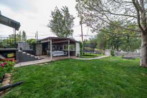 Expansive green lawn with a covered patio area, concrete steps, and established trees