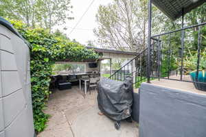 Covered outdoor living space featuring concrete patio flooring, an integrated counter, and a built-in entertainment area