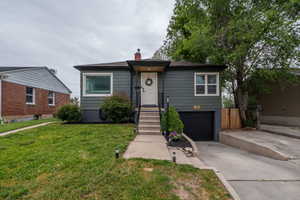 Front exterior featuring dark gray siding, white trim windows, and garage door