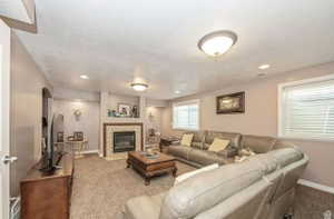 Living area featuring a tiled fireplace with wood mantle, neutral wall paint, recessed lighting, and white window blinds