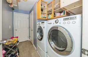 Dedicated laundry area featuring floor-mounted appliances, overhead wooden cabinetry, and tile flooring