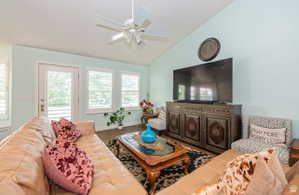 Living space with vaulted ceilings, wood-finish flooring, and light blue walls